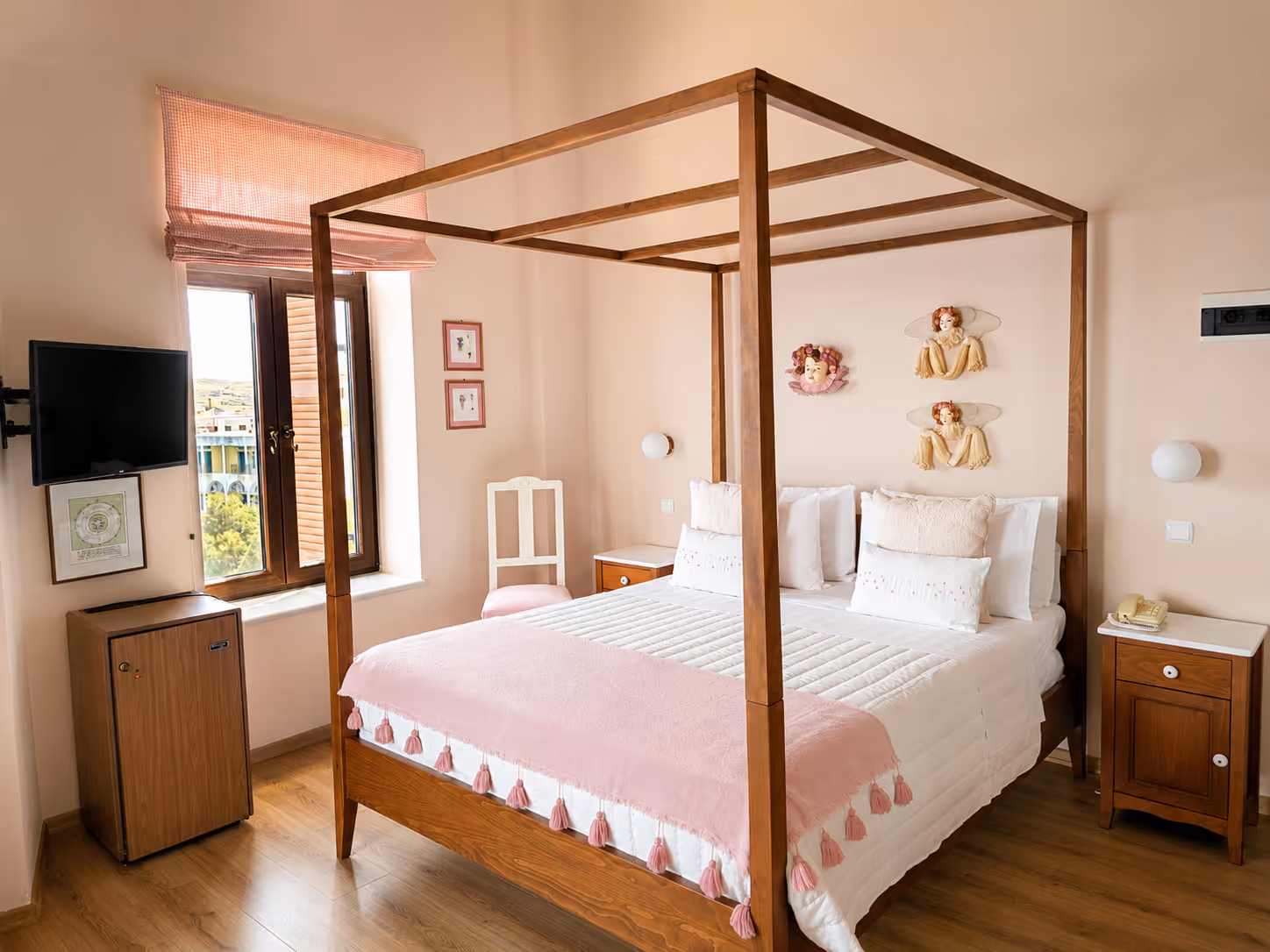 Bedroom with wooden canopy bed, pink blanket, white walls, small TV, window, and bedside tables.